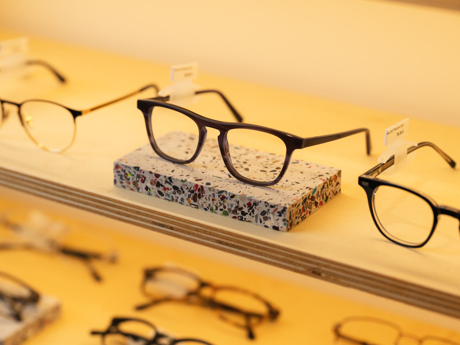 Une monture posée sur un support en Terrazac, au milieu d’autres lunettes en présentation.